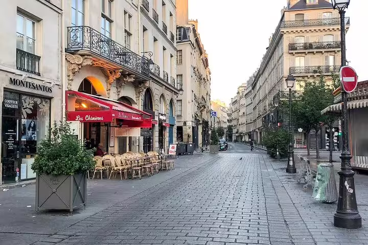 Cobblestone street in Le Marais Paris with red-awning café Les Chimères and classic Haussmann buildings