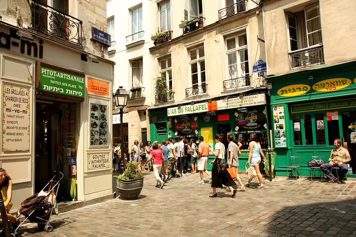 Busy pedestrian street in Le Marais Paris with falafel shops and tourists walking