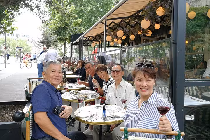 Group of friends enjoying wine and food at a Parisian outdoor café terrace in Le Marais