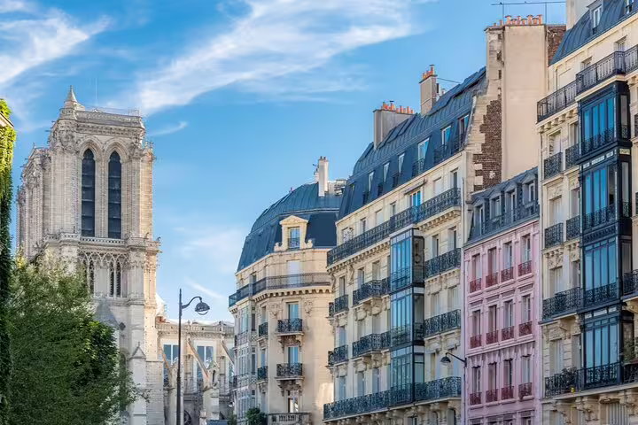 Haussmann apartment buildings and Gothic cathedral tower in Le Marais neighborhood, Paris