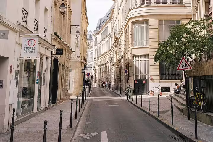 Narrow Parisian street in Le Marais with Haussmann buildings and a sports shop