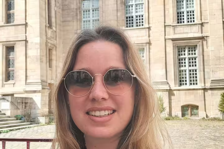 Smiling woman with sunglasses on Le Marais walking tour in Paris with historic building behind