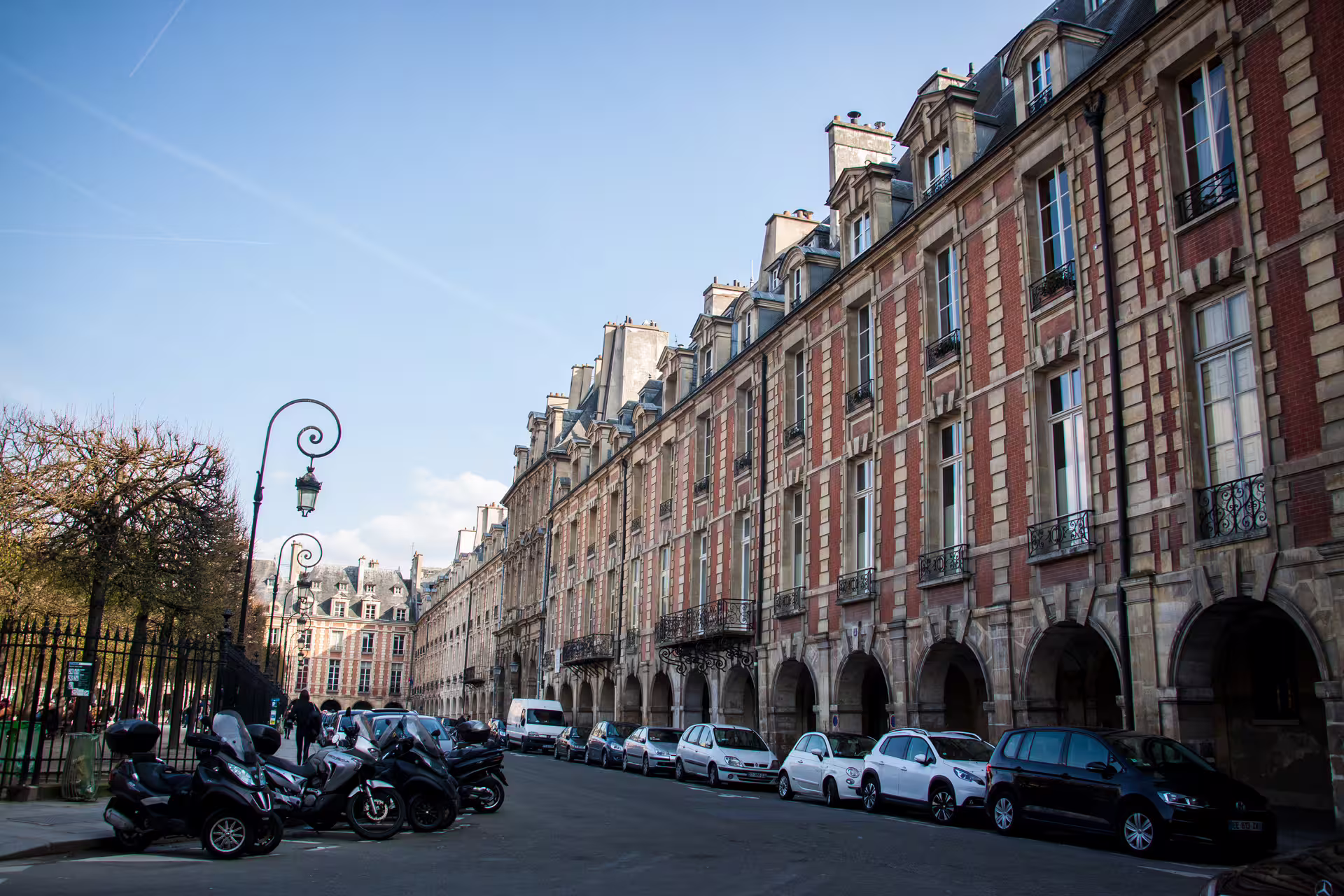 Historic red brick facades and arched arcades lining Place des Vosges in Le Marais, Paris