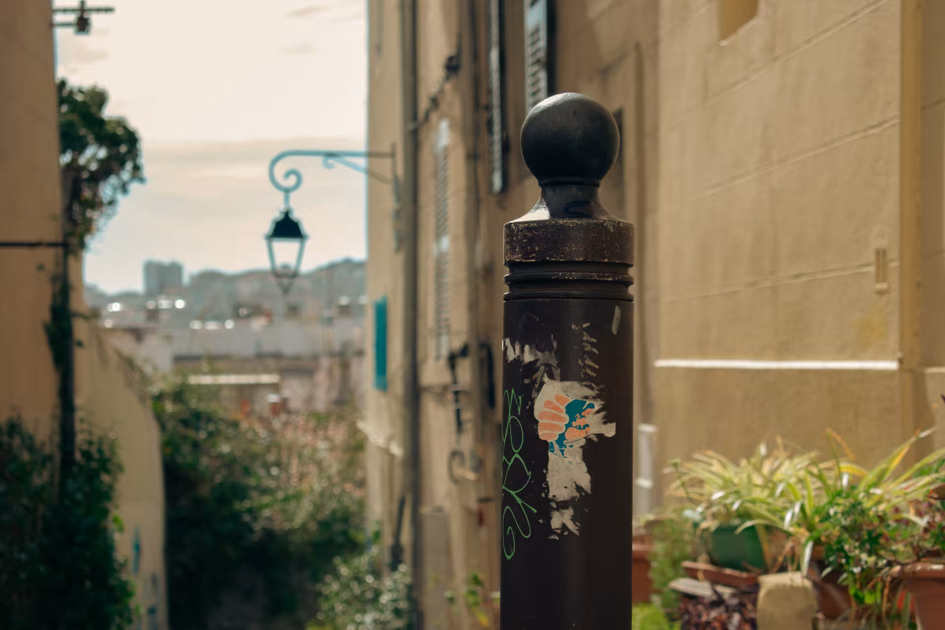 Narrow Le Panier alley in Marseille with vintage streetlamp and plants, captured on an Old Town walking tour