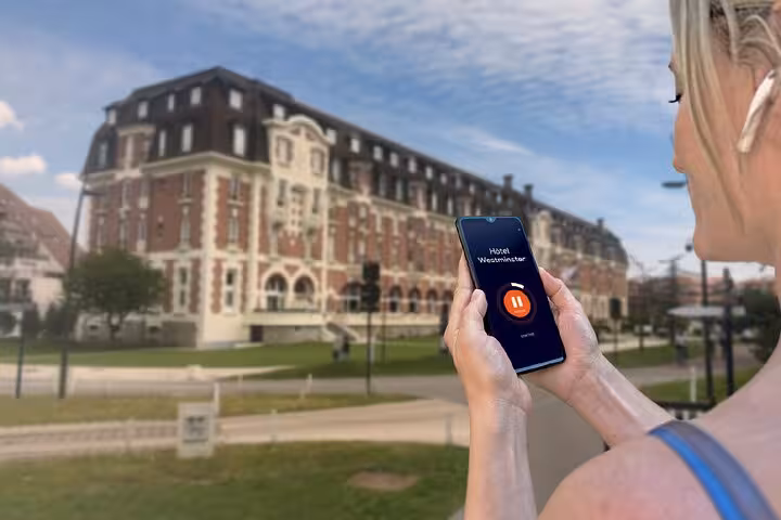 Woman holding smartphone with Hotel Westminster audio guide app during Le Touquet self-guided walking tour
