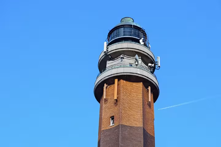 Brick lighthouse tower with green lantern room against clear blue sky in Le Touquet