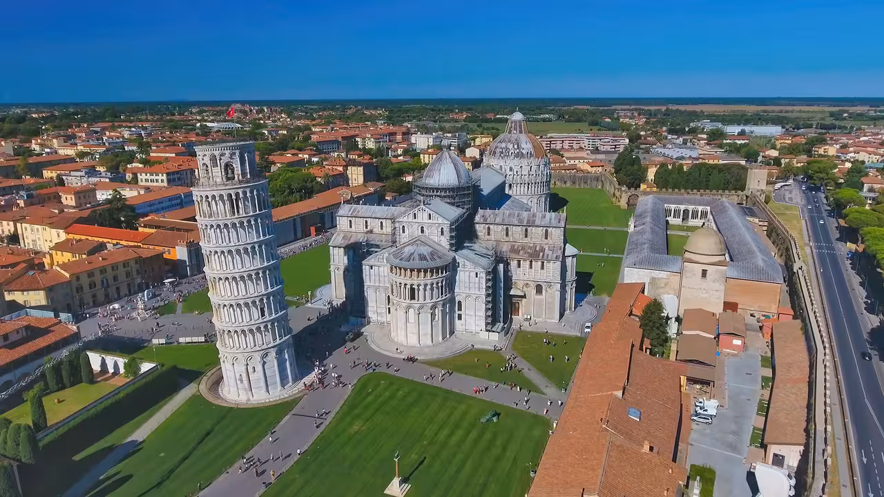 Aerial view of the iconic Leaning Tower of Pisa and surrounding historic architecture on a sunny day.