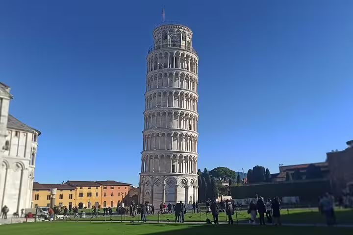 Travelers admiring the Leaning Tower of Pisa on a clear day, a highlight of the private Pisa and Lucca farm tour