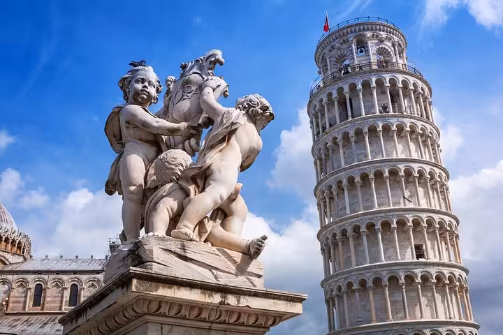 Statue and Leaning Tower of Pisa under blue sky featured in full day private Tuscany tour from Florence.