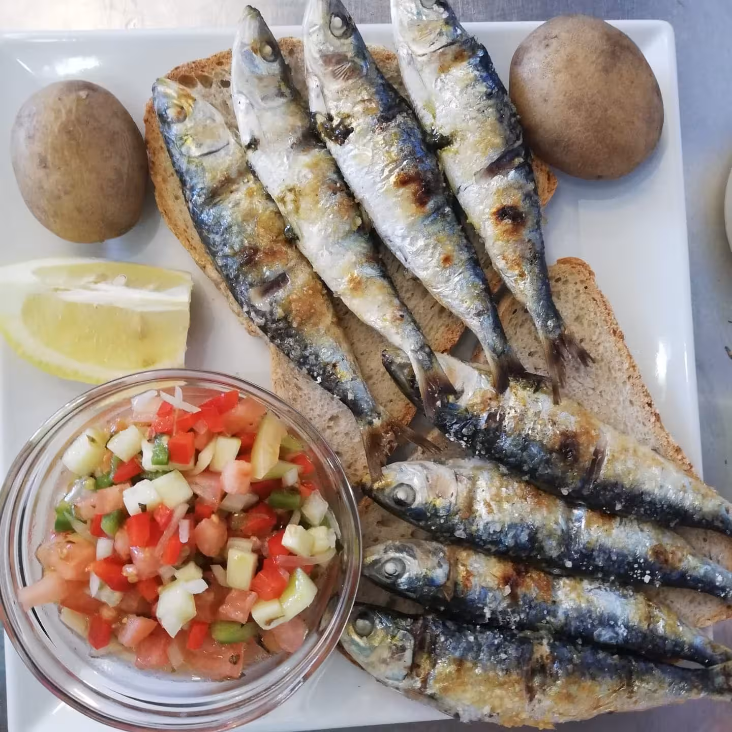 Traditional Leeward Islands grilled sardines on rustic bread with tomato salsa, potatoes and lemon on a local food tour