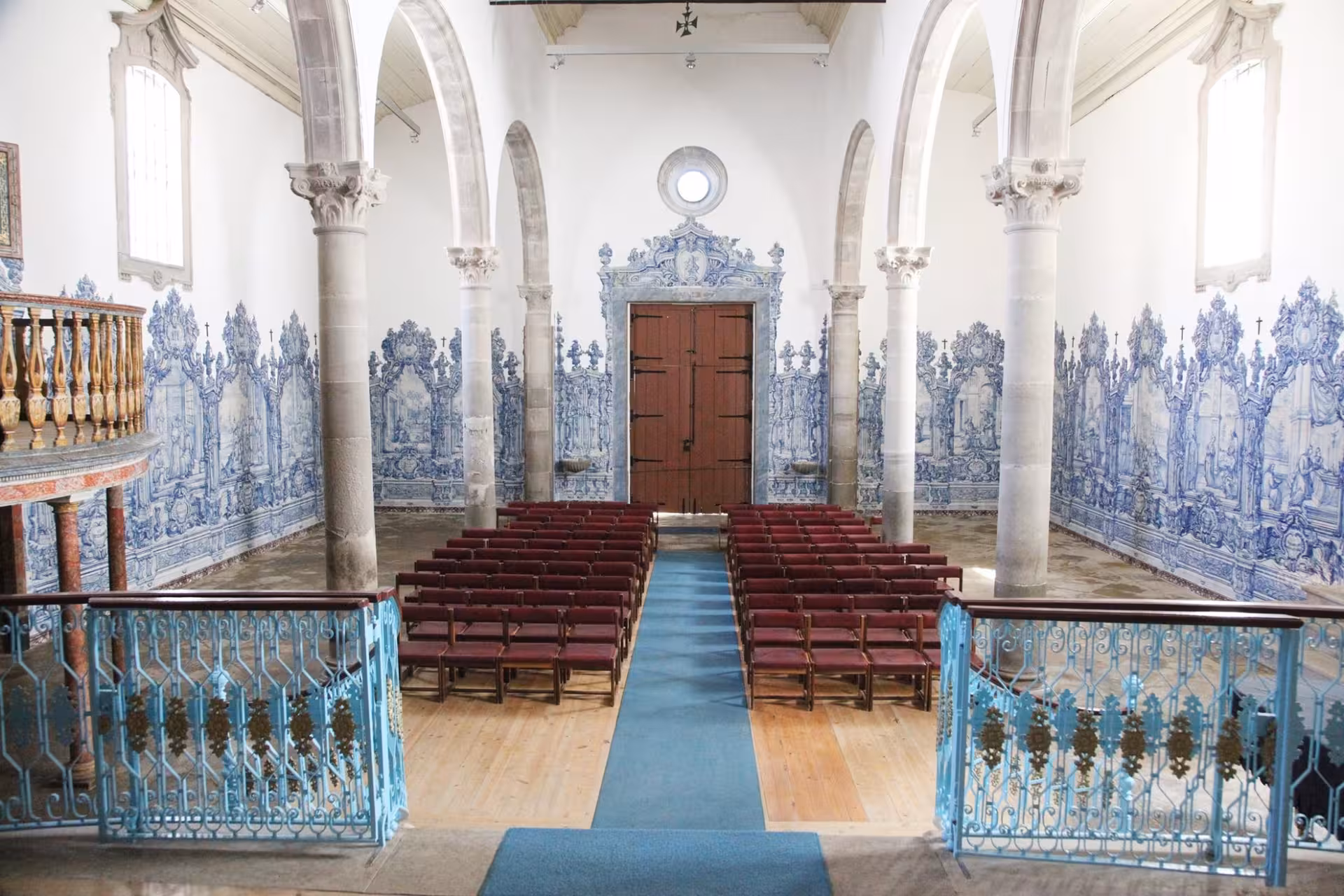 Historic Leeward Islands church interior with blue azulejo tiles, stone arches and rows of seats for cultural tours