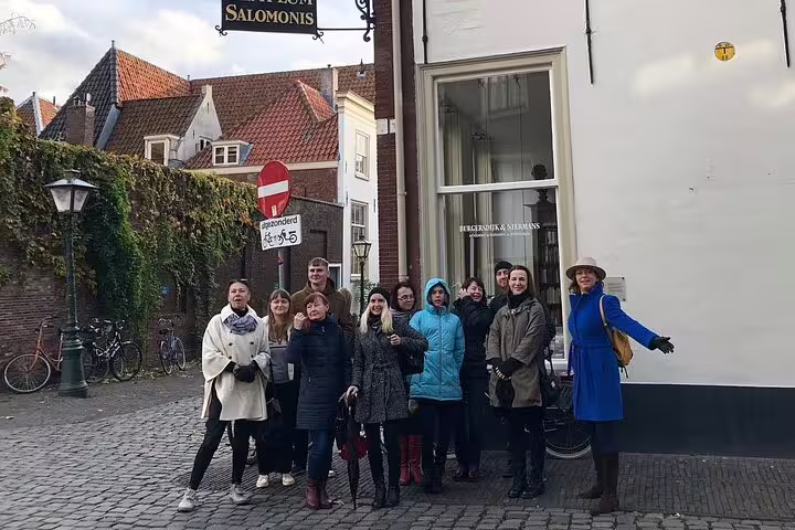 Private guided Leiden walking tour group on cobbled street by historic canal houses in the Dutch old town