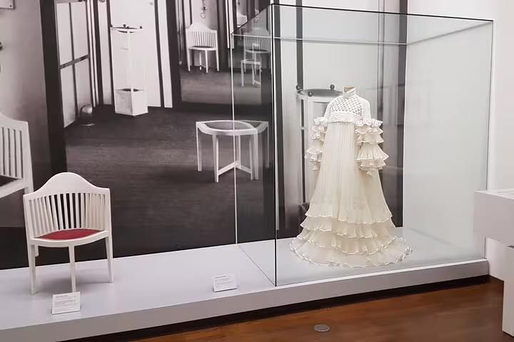 Exhibit of a white Art Nouveau dress in a glass case at the Leopold Museum, showcasing Viennese artistic heritage.