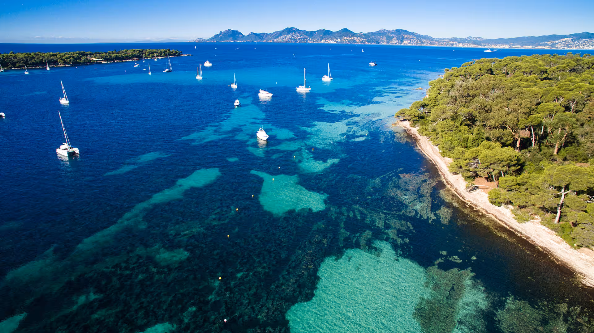 Aerial view of turquoise waters around Lerins Islands near Cannes with sailboats anchored offshore