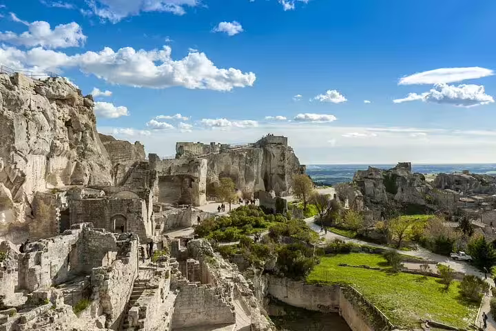 Ancient ruins and rocky cliffs of Les Baux-de-Provence with green valley and blue sky