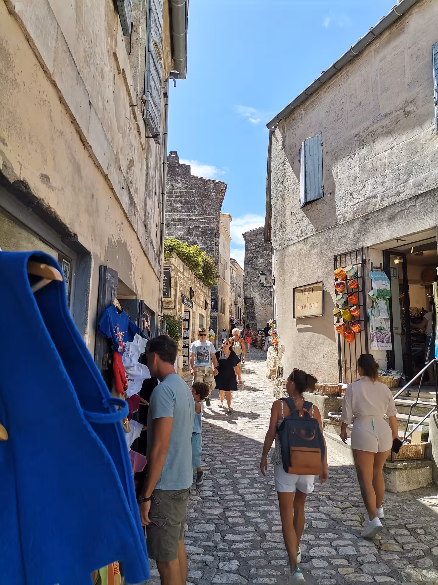 Cobblestone street market in Les Baux-de-Provence with shops and visitors, authentic Provence lifestyle tour