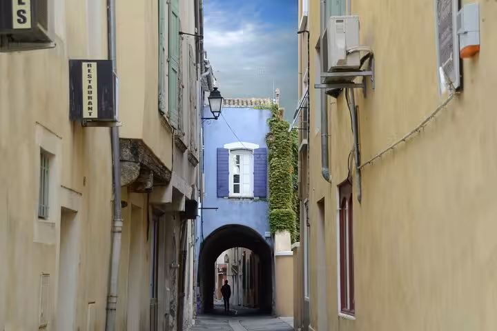 Charming narrow street in Les Baux de Provence with colorful shutters and historic architecture.