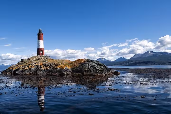 Les Eclaireurs Lighthouse standing on a rocky island with mountain backdrop in the Beagle Channel, Ushuaia.