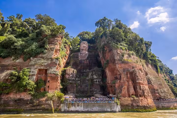 View of the majestic Leshan Giant Buddha carved into a lush cliffside in Sichuan, a highlight of Chengdu tours.