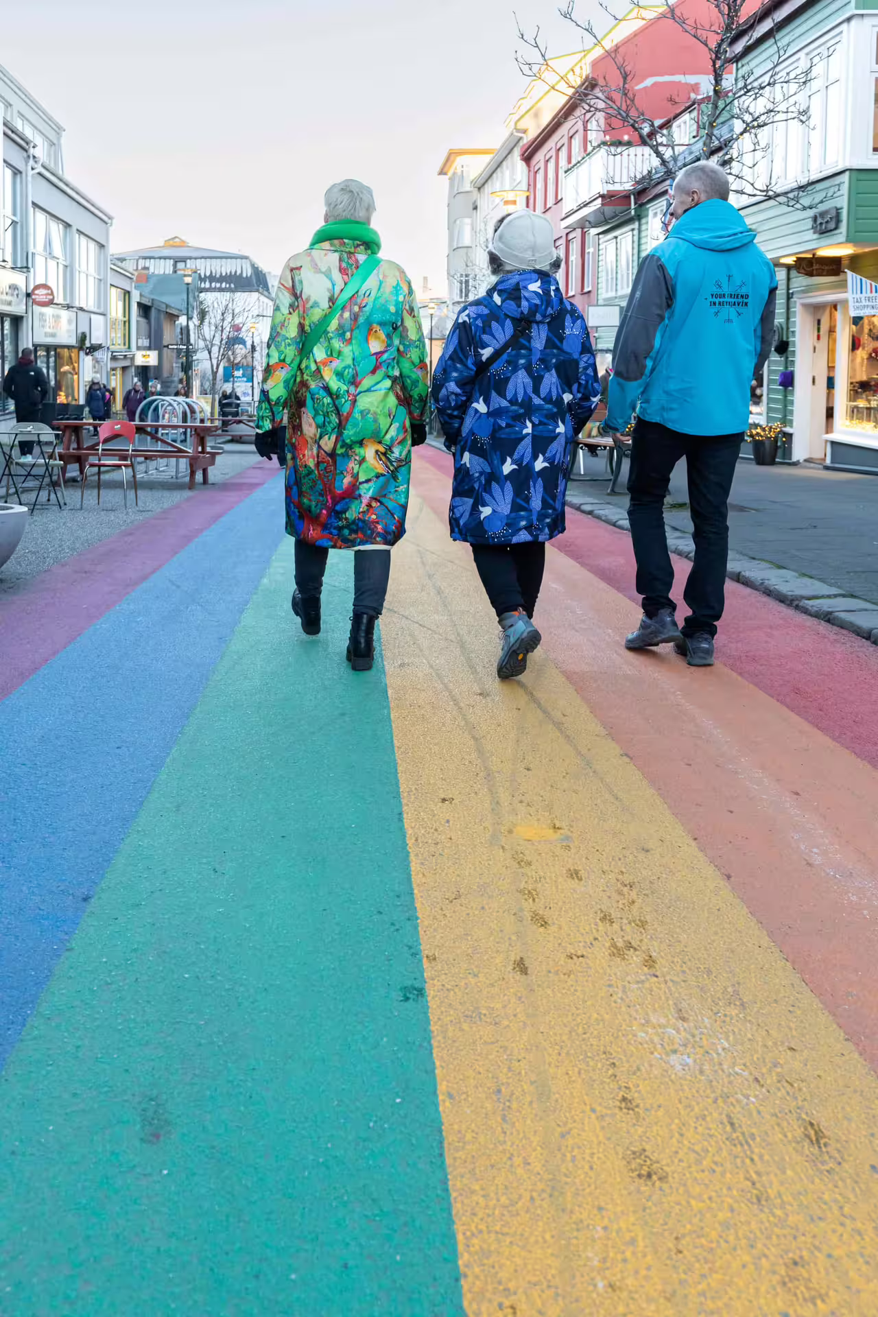 Three people walking on rainbow-painted street in downtown Reykjavik during LGBTQ walking tour