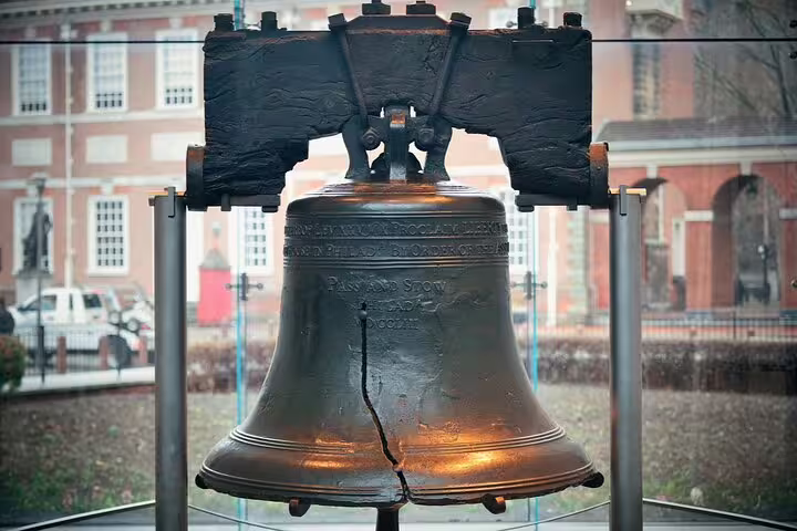 Liberty Bell with visible crack on display in Philadelphia with Independence Hall in background
