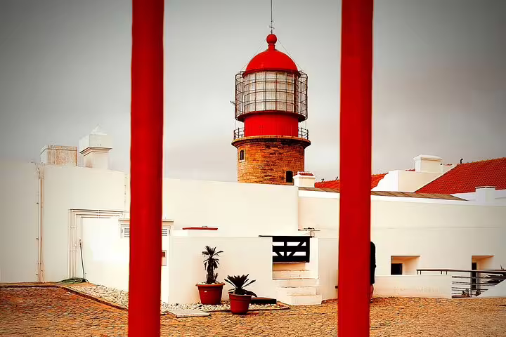Historic red-topped lighthouse framed by vibrant architecture on a scenic West Coast 4x4 Natural Park tour.
