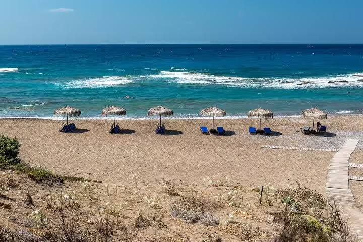 Limni beach on Rhodes with straw umbrellas and sunbeds by turquoise Aegean waters on a private car day trip