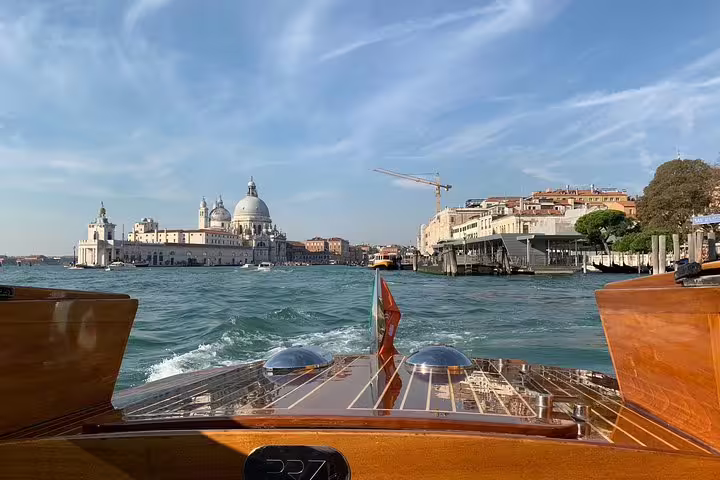 Elegant view from a LimoBoat cruising towards the iconic architecture of Venice's Grand Canal under a clear sky.