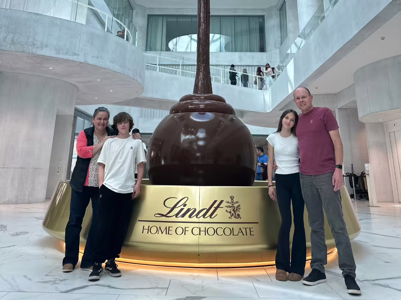 Family enjoying Lindt Home of Chocolate tour in Zurich with a giant chocolate fountain centerpiece.