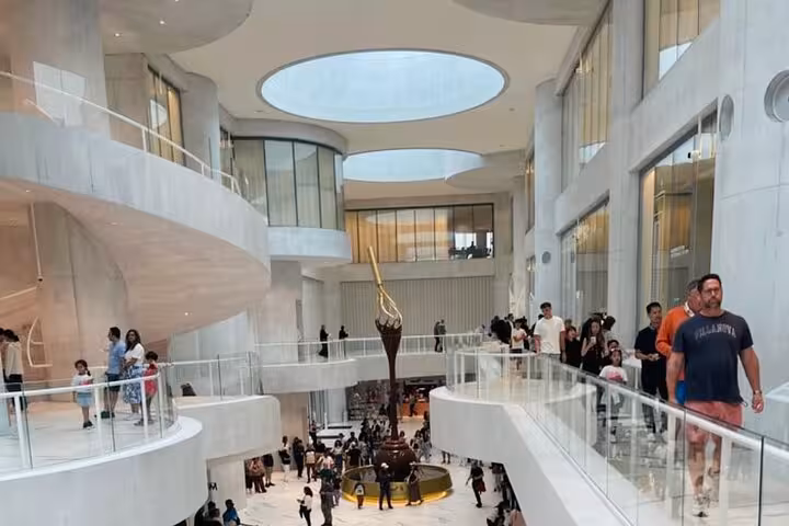 Lindt Home of Chocolate Museum Zurich atrium with chocolate fountain, visitors, and pickup drop-off tickets