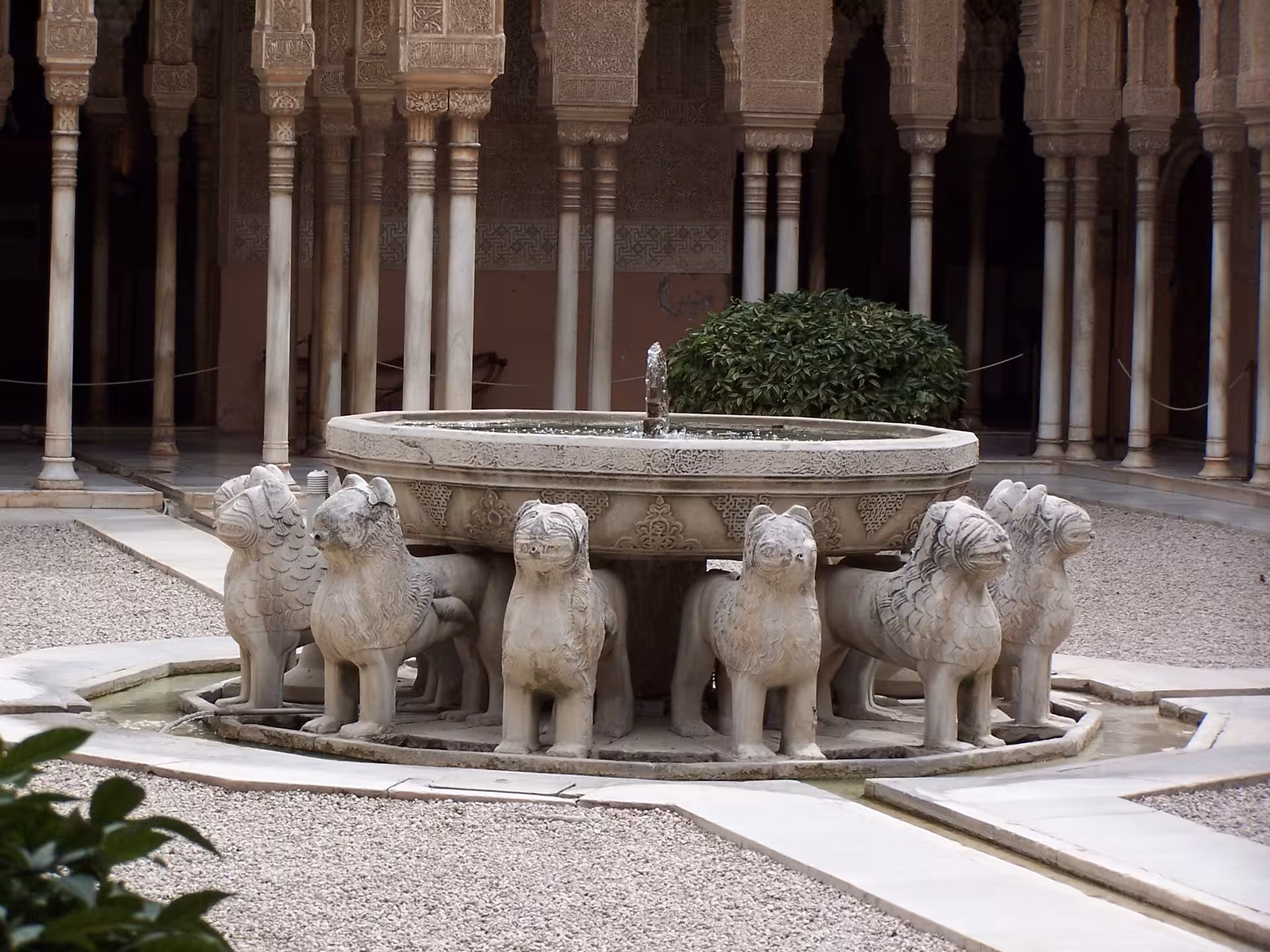 Intricate Lion Fountain in the Court of the Lions, Alhambra, featuring detailed stone lion sculptures and arches.
