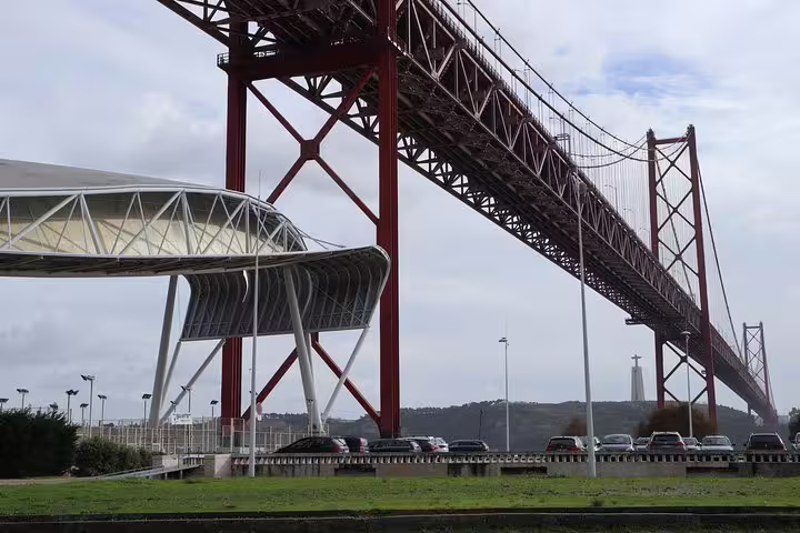 View of the striking 25 de Abril Bridge in Lisbon with modern architecture and the Cristo Rei statue in the distance.