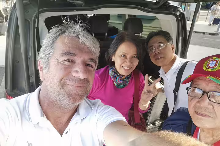 Group of travelers smiling inside a Lisbon airport shuttle van, showcasing convenient and friendly transportation service.