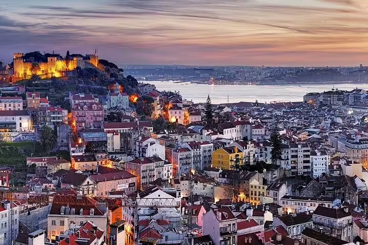 Scenic Lisbon cityscape at sunset showcasing vibrant rooftops and historic architecture, ideal for private airport transfers.