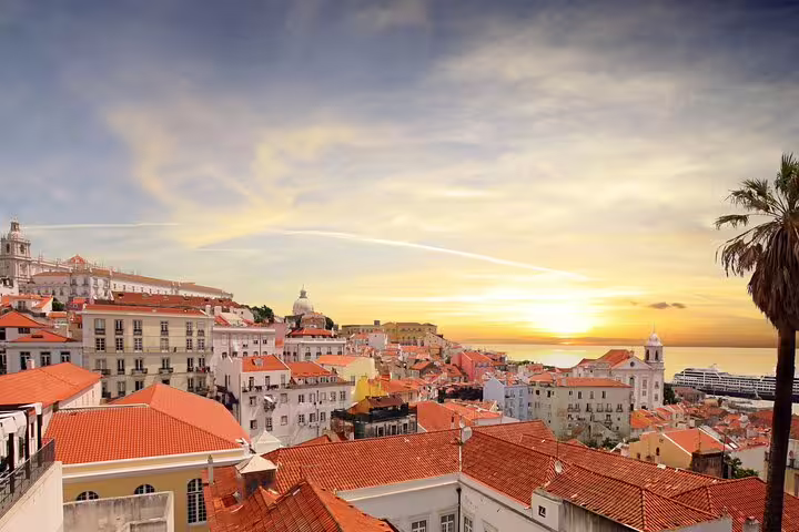 Scenic view of Lisbon's historic Alfama district at sunrise, showcasing colorful rooftops and a vibrant skyline for a private tour.