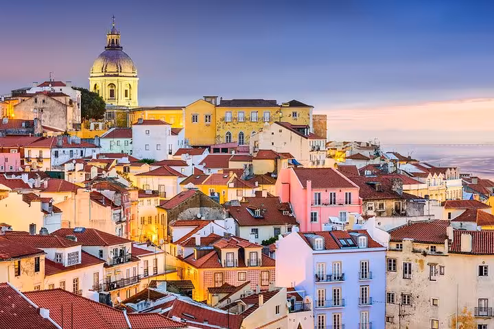 Scenic view of Lisbon's colorful Alfama district with iconic dome under twilight sky, perfect for private tours.