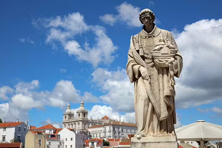 Stone statue of Saint Vincent holding Lisbon model with São Vicente de Fora monastery in background