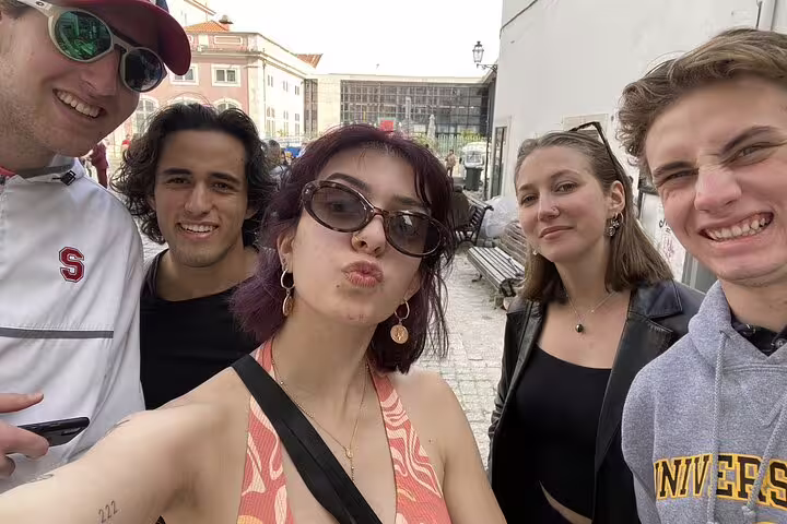Group of five young tourists smiling for a selfie on a Lisbon street during a city discovery tour