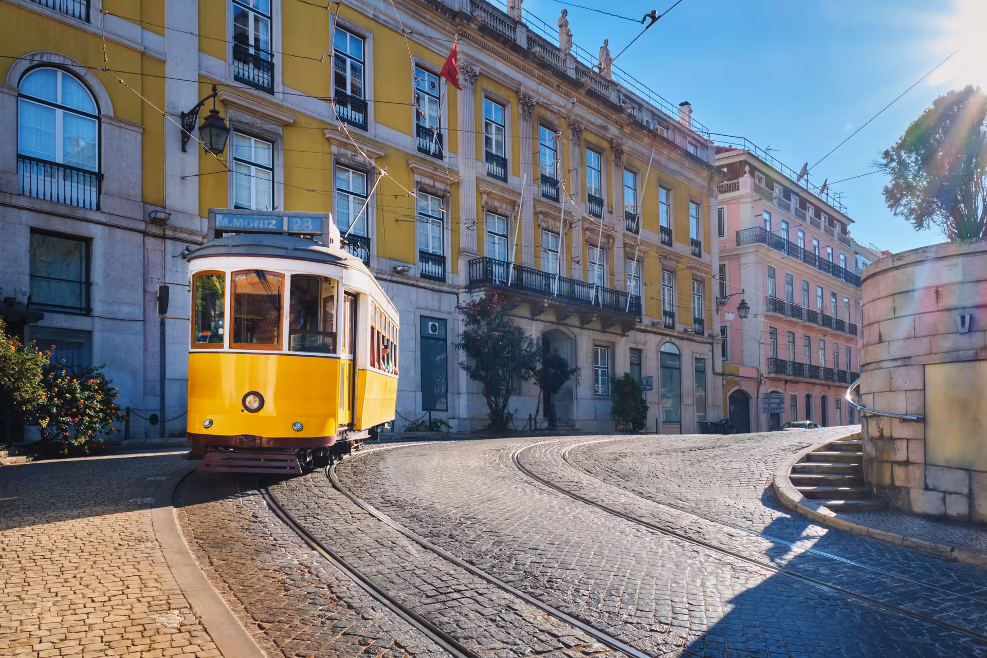 Iconic yellow tram 28 navigating cobblestone streets of Lisbon Alfama district on a historic old town walking tour