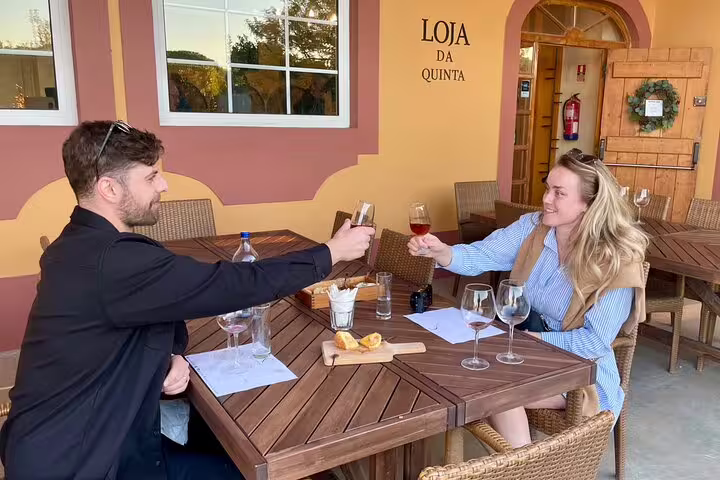 Two people enjoying wine tasting at an outdoor table during the Private Full Day Setúbal & Arrábida Wine Tour near Lisbon.