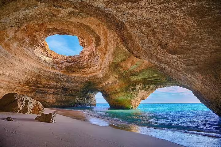 Scenic Lisbon to Barcelona coastal tour featuring stunning sea caves with turquoise waters and sunlit rock formations.