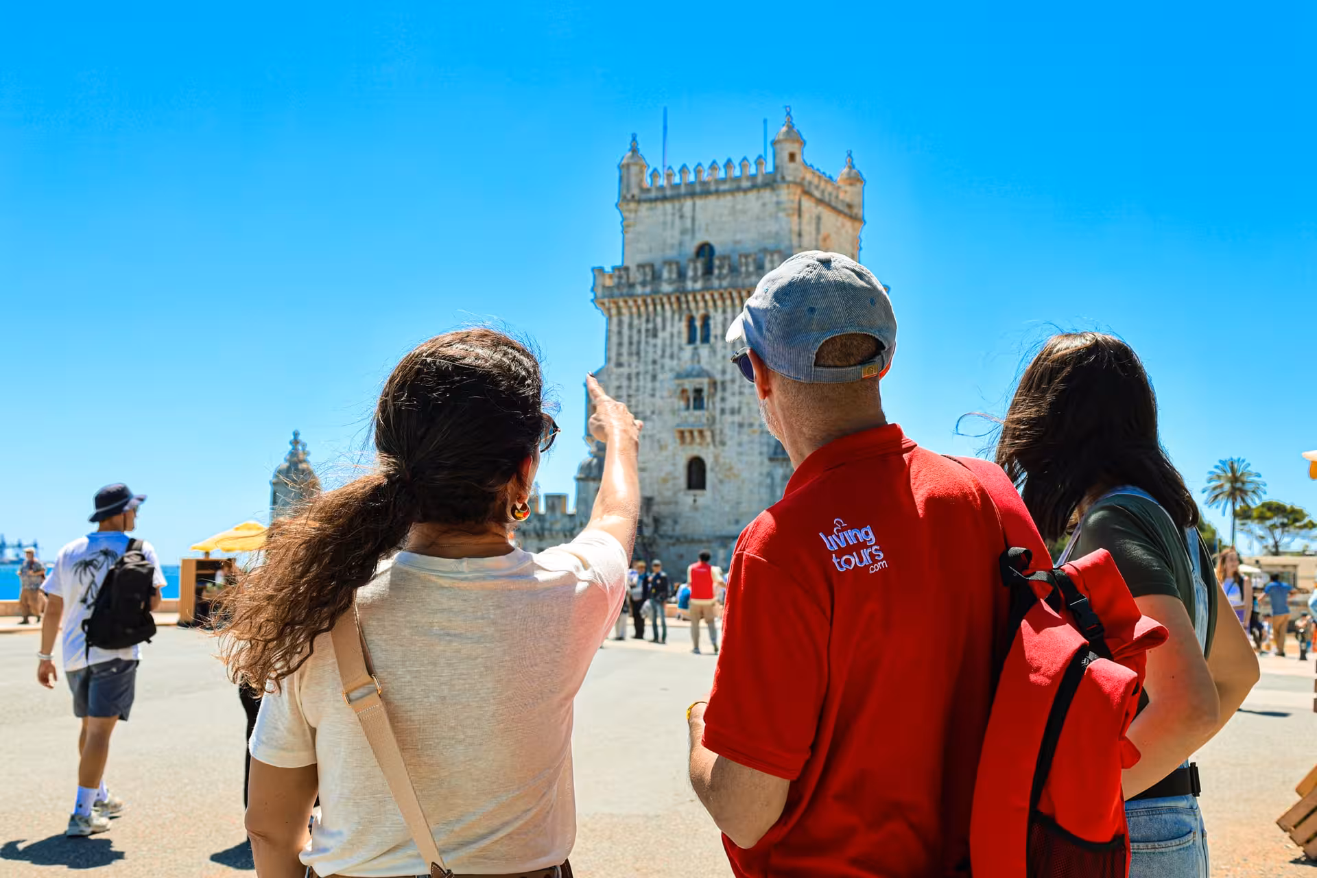 Tour guide showing visitors the historic Belém Tower on a sunny Lisbon half-day city tour.