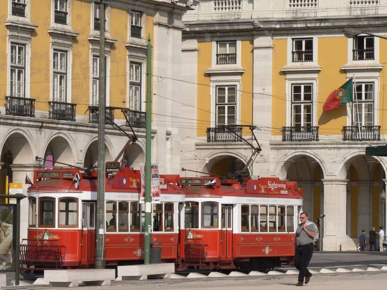 Historic red tram passes through Lisbon's Praça do Comércio, capturing the city's charm and vibrant culture.