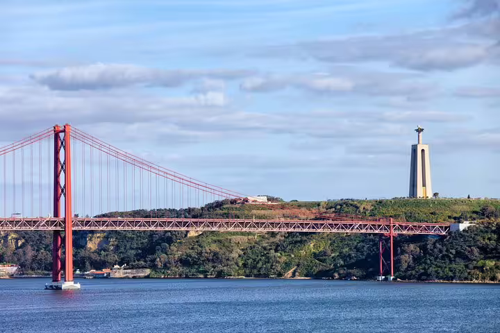 View of Lisbon's iconic 25 de Abril Bridge and Cristo Rei statue, perfect for a scenic ferry tour to Cacilhas with local food and drink.