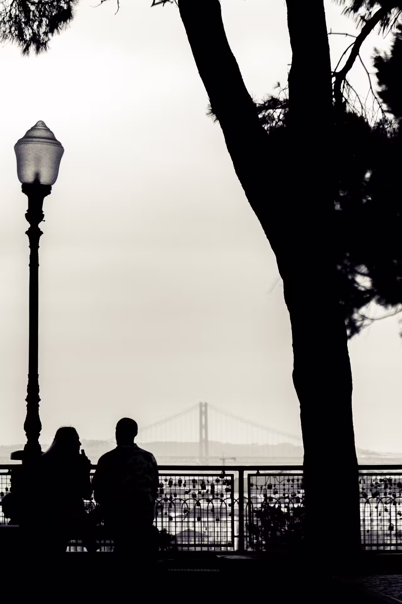 Silhouetted couple enjoying Lisbon's scenic sunset with iconic bridge view on private photo walk tour.