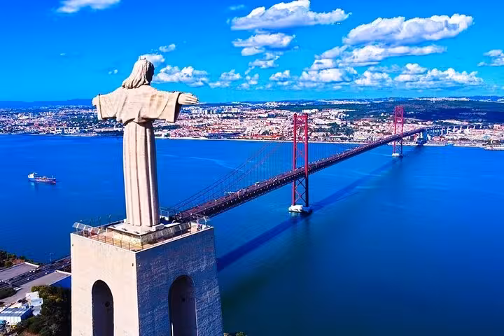The Cristo Rei statue overlooking the 25 de Abril Bridge with a panoramic view of Lisbon's skyline.