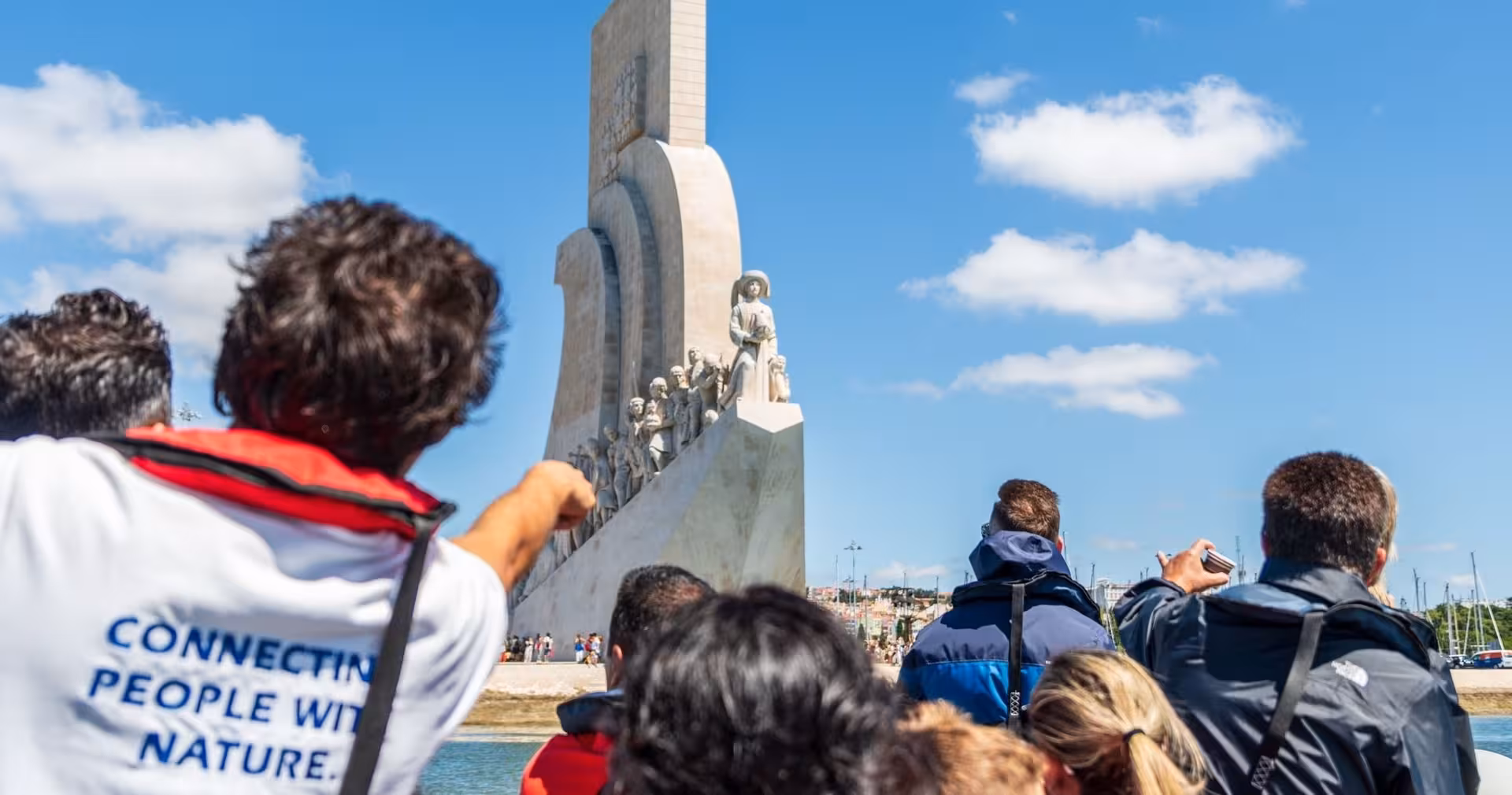 Guests on a Lisbon dolphin watching boat pass the Padrão dos Descobrimentos monument on the Tagus River