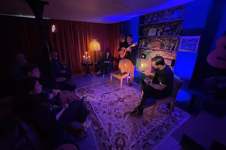 Audience enjoying live Fado performance with musicians in a cozy, blue-lit Lisbon venue adorned with candles.