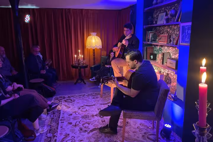 Intimate Lisbon Fado concert with musicians playing guitar, surrounded by cozy candlelit ambiance.