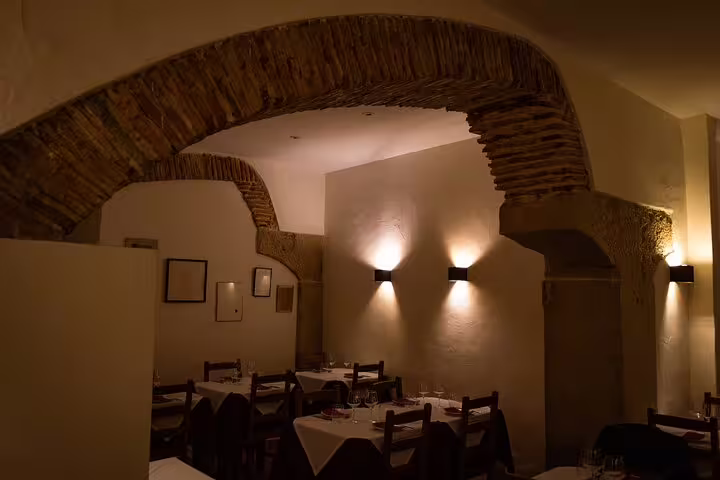 Cozy Lisbon restaurant interior with rustic brick arches, warmly lit for a Fado dinner show experience.